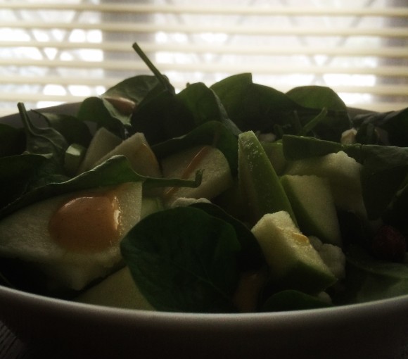 Salad featuring baby spinach, green apples, goat cheese, almonds, and honey dijon dressing.